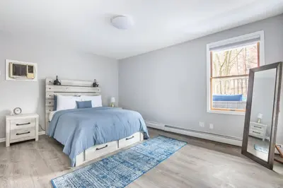 a white bedroom with a bed and a mirror at Sleek 1 Bedroom Apartment Plus Balcony 30 Mins to NYC in New Rochelle