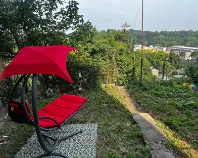 a red chair with a red umbrella in the grass at 10-A Diamond in Yonkers, NY in Yonkers
