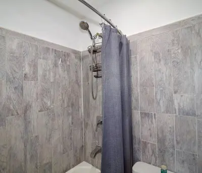 a shower with a blue shower curtain in a bathroom at Tuk Ahoy - Emerald Suite 3C with Shared Spaces in Brooklyn