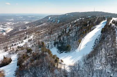 a snow covered hill with trees and a ski slope at Brentwood Burrow in East Stroudsburg