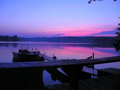 a boat is docked at a dock with a sunset at Captains Cabin - Cozy Cabin in Laurel Island in East Hampton