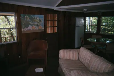 a living room with a couch and a table and windows at Cabin Chalet - Breathtaking Cabin in Laurel Island in East Hampton