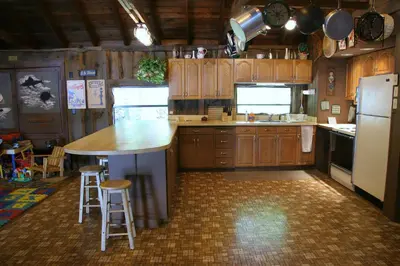 a kitchen with wooden cabinets and a kitchen island with stools at Cabin Chalet - Breathtaking Cabin in Laurel Island in East Hampton