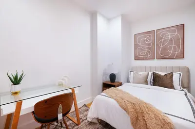 a bedroom with a desk and a bed with white sheets at 1290-6 Newly Renovated 2 Bedrooms in UES in New York