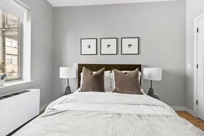 a white bedroom with a large bed with two lamps at Top Notch 2BR in Upper East Mins to Central Park in New York