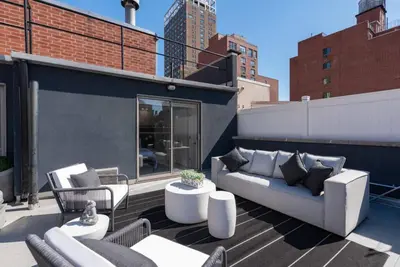 a patio with a couch and chairs on a rooftop at 3BR Penthouse Suite with Massive Private Rooftop in New York
