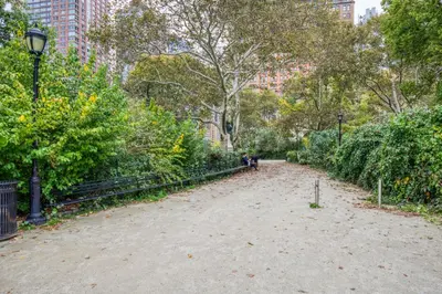 a dirt path in a park with trees and bushes at FiDi 1br w game room resident-only speakeasy NYC-1346 in New York