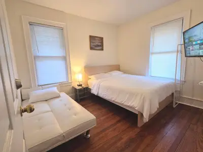 a bedroom with a bed and a couch and two windows at Entire Beautiful 2BR Private Apartment [R] in Whitestone