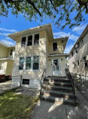 a white house with stairs in front of it at Entire Cozy 1BR Apartment in heart of Queens L in Whitestone