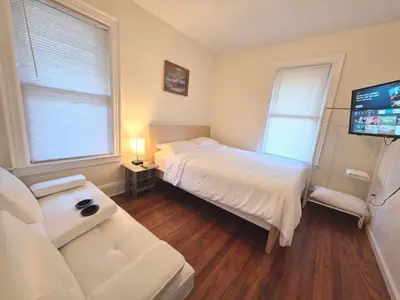 a bedroom with a bed and a couch and a tv at Entire Beautiful 1BR for You! [R] in Whitestone