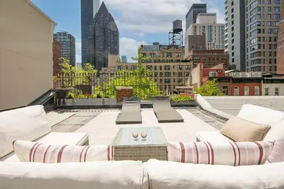 a rooftop patio with white furniture and a city skyline at Private Penthouse w Roof Oasis in New York