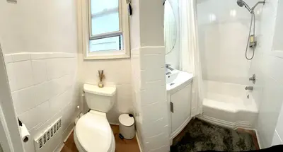 a white bathroom with a toilet and a sink at 7-A Diamond in Yonkers in Yonkers