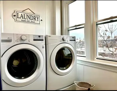 a white washing machine in a laundry room with windows at 7-A Diamond in Yonkers in Yonkers