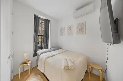 a white bedroom with a bed and a tv at Oasis Room at a Shared Apartment by Times Square in New York