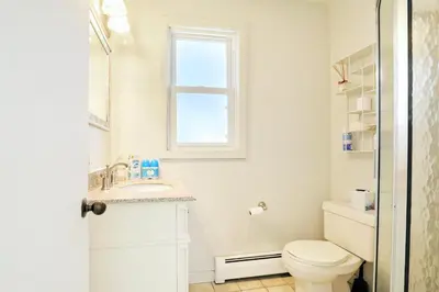 a bathroom with a toilet and a sink and a window at Cheerful 3 Bedroom Beach Front Cottage with Fire Place in Milford