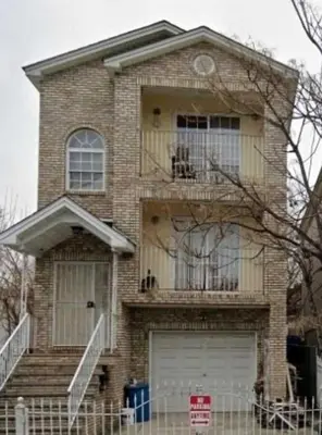 a brick house with a balcony and a garage at Room J Divine Villa and Resorts 5mins to EWR Airport and 4mins to Penn Station Newark, New York in Newark