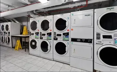 a row of washing machines in a laundry room at 73-1503 Newly Reno Studio UWS Doorman Gym Laundry in New York