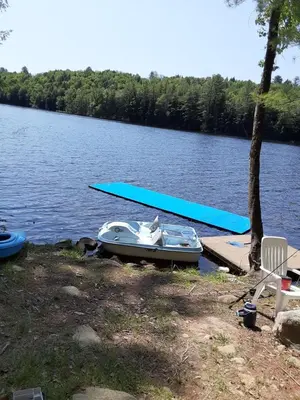 a boat is parked on a dock on a lake at Riverfront Ritz campsite in Lake Luzerne