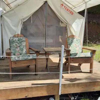 a tent with a wooden table and two chairs at Tentrr Riverfront Ritz in Lake Luzerne