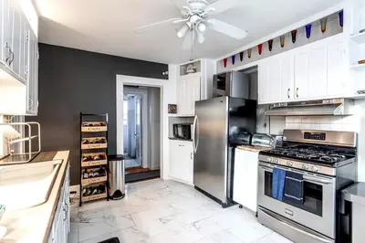 a kitchen with a stainless steel refrigerator and white cabinets at Stamford Bohemian by HarborPoint Downtown &Train in Stamford