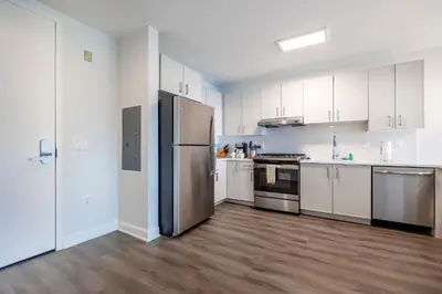 a kitchen with white cabinets and a stainless steel refrigerator at Private Apt with Gym & Pool in Stamford