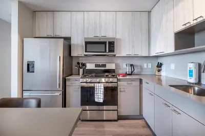a kitchen with stainless steel appliances and white cabinets at Trendy Apt On Harbor with Gym in Stamford