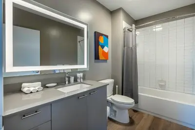 a bathroom with a sink and a toilet and a mirror at Trendy Apt On Harbor with Gym in Stamford