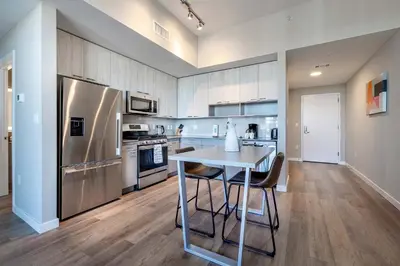 a kitchen with a table and a stainless steel refrigerator at Trendy Apt On Harbor with Gym in Stamford