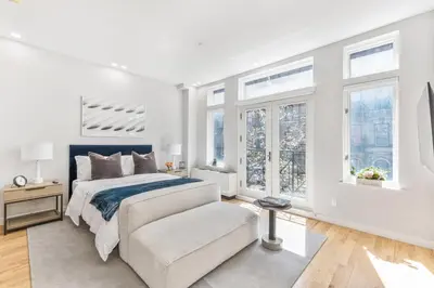 a white bedroom with a bed and a chair at Studio w Charming Juliet Balcony in Upper East in New York