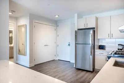 a kitchen with a stainless steel refrigerator and white cabinets at Private Luxury Apt with Gym in Stamford