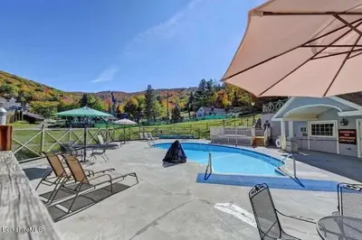 a swimming pool with chairs and an umbrella at Game Night Suite at Jiminy Peak Ski OnOff Sleeps 4 in Hancock