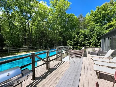 a wooden deck with a swimming pool and chairs at Luxury Woodstock Retreat Hot tub heated pool in Woodstock