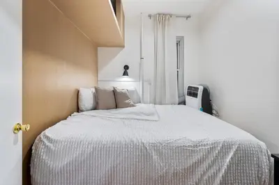 a bedroom with a bed with a white comforter at Spacious 2BR on the Upper East Side Steps from Central Park in New York