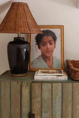 a lamp on a wooden table with a painting and a picture at The Bend Micro Resort in Phoenicia