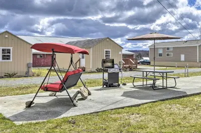 a patio with a table and a chair and an umbrella at The Hideout Cottage Close to Ski Mountain in Pleasant Mount