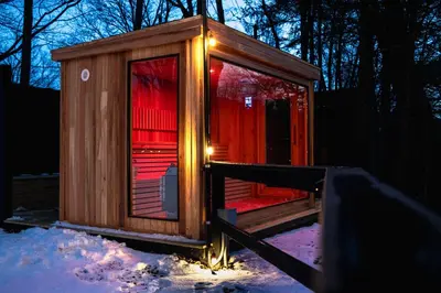 a small wooden cabin with lights in the snow at Perch Cottages #7 - Creek Access, Sauna, Mt views in Boiceville