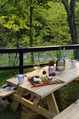 a picnic table with wine glasses and food on it at Perch Cottages #13 - Creek Access, Sauna, Mt views in Boiceville