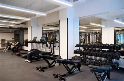 a gym with lots of treadmills and weights at NEW Modern 2BR w Fireplace & Fitness Lounge, Live Comfortably in East Harlem in New York