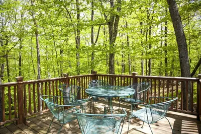 a table and chairs on a deck with trees at Country Getaway Nestled in Enchanting Westchester County near New York City in Bedford