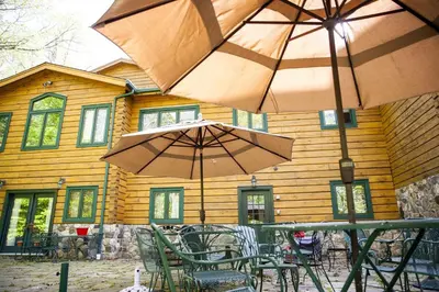 two tables and chairs with umbrellas in front of a building at Country Getaway Nestled in Enchanting Westchester County near New York City in Bedford