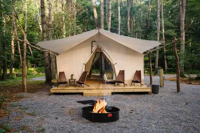 a tent with chairs and a fire in front of it at Luxury Group Safari Tent Complete with Firepit and Patio, Perfect for a Weekend Escape to the Adirondacks in Corinth