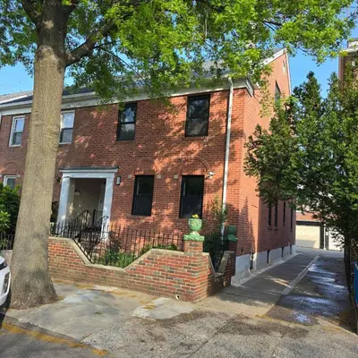 a red brick building with a tree in front of it at Astoria, steps away from Manhattan in Astoria