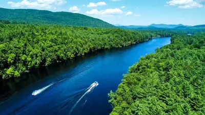 a boat traveling down a river in the woods at Classic Safari Tent in the Heart of the Adirondack Wilderness, near Lake George, New York in Corinth