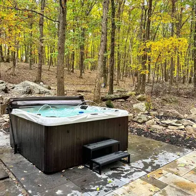 a hot tub in the middle of a forest at Mahogany Sun Hot Tub Theater Room Fire Pit in East Stroudsburg