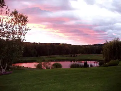 a pond in a field with a sunset in the sky at Gorgeous Getaway Suite in a Converted Barn near Hudson, New York in Hudson