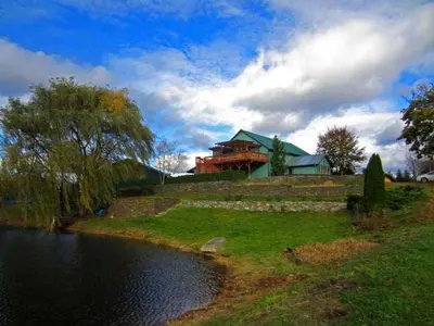 a house sitting on top of a hill next to a river at Pet-Friendly Vacation Rental on a Working Farm near Hudson, New York in Hudson