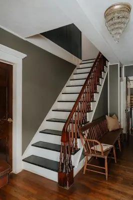 a staircase in a house with a chair and a chandelier at Book Village Inn - Dickinson Room Queen Bed in Hobart