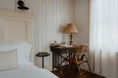 a bedroom with a bed and a desk with a lamp at Book Village Inn - Dickinson Room Queen Bed in Hobart