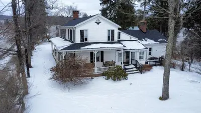 a white house with snow on the ground at Book Village Inn - Fitzgerald Room King Bed in Hobart