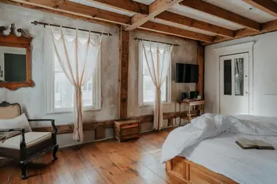 a bedroom with a bed and a chair and windows at Book Village Inn - Entire Hotel in Hobart